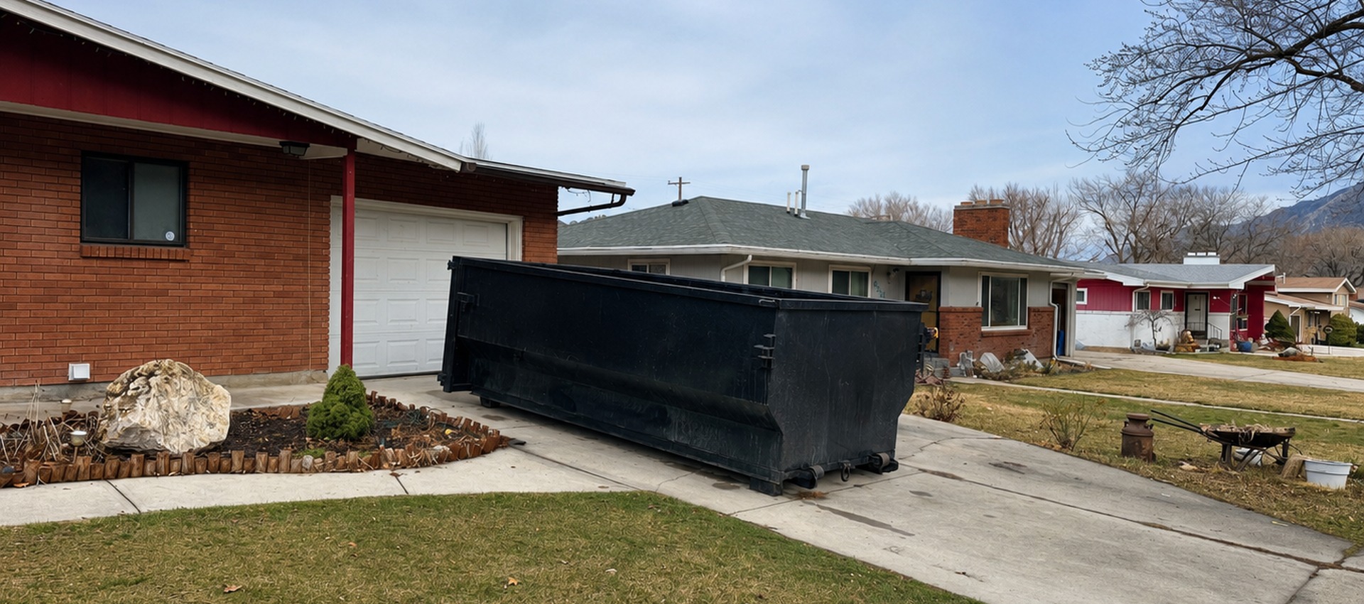 Black dumpster at a residential property for a junk removal marketing agency service page