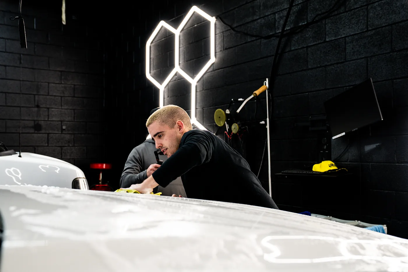 Auto detailer wiping a truck under paint-correction lights